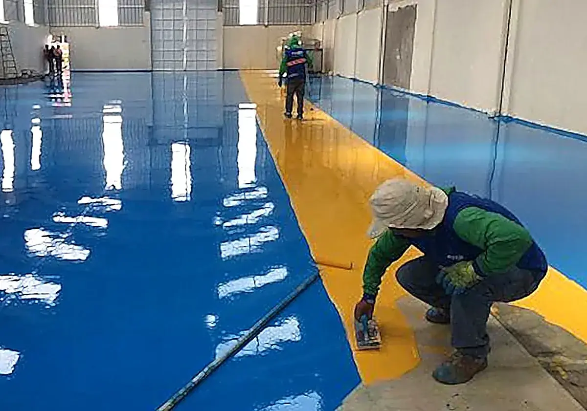 Aplicadores colando piso epóxico azul y amarillo